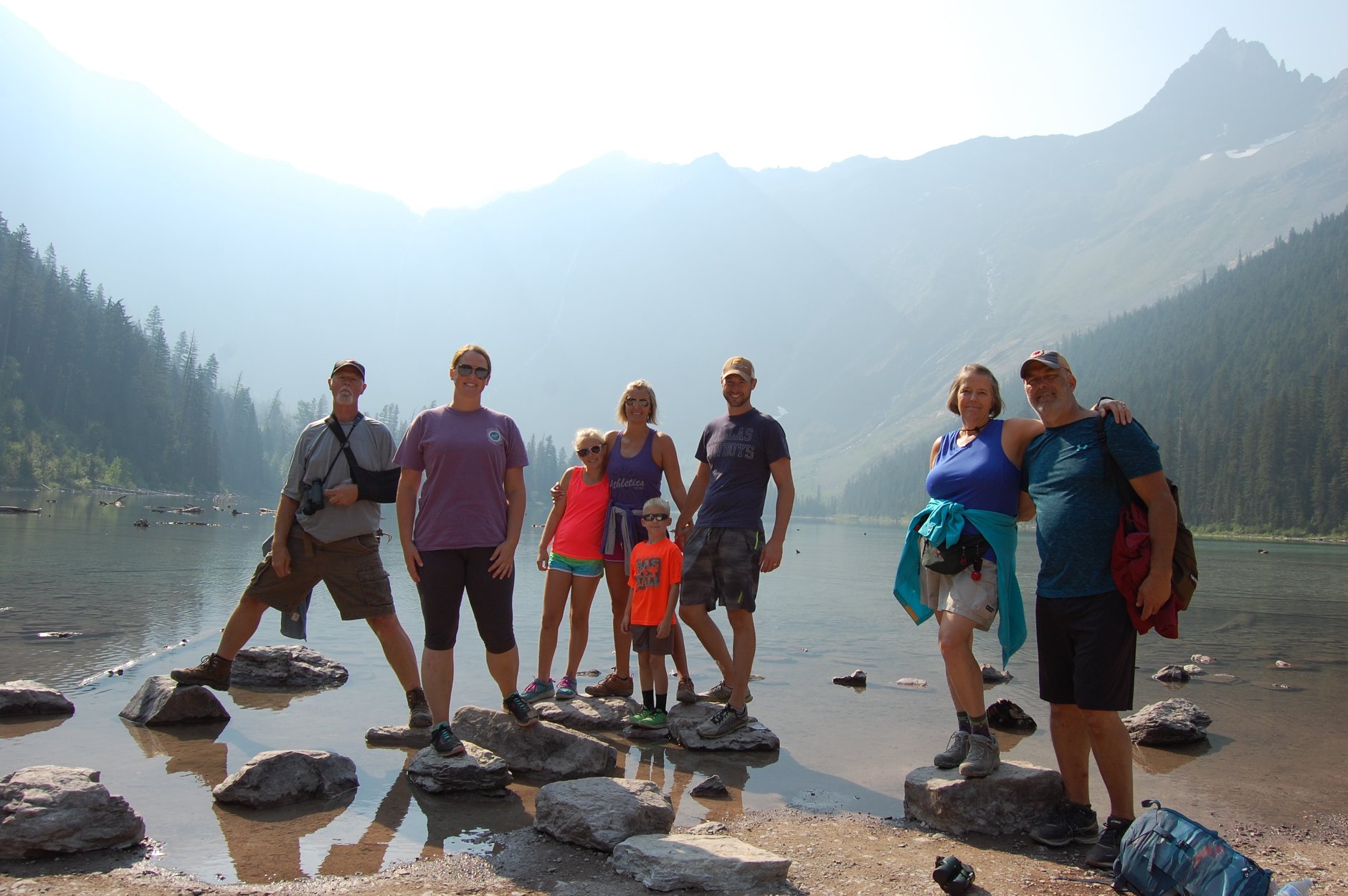 Family in front of lake and mountains on rocks