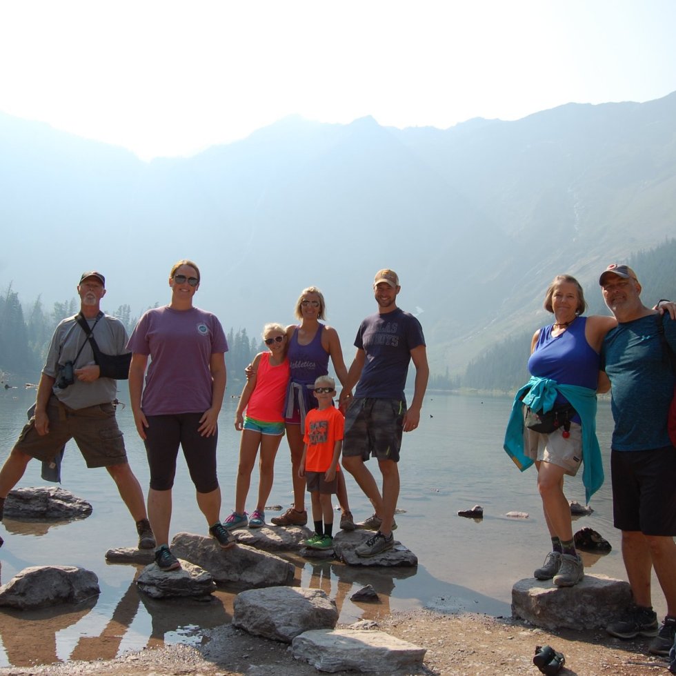 Family in front of lake and mountains on rocks