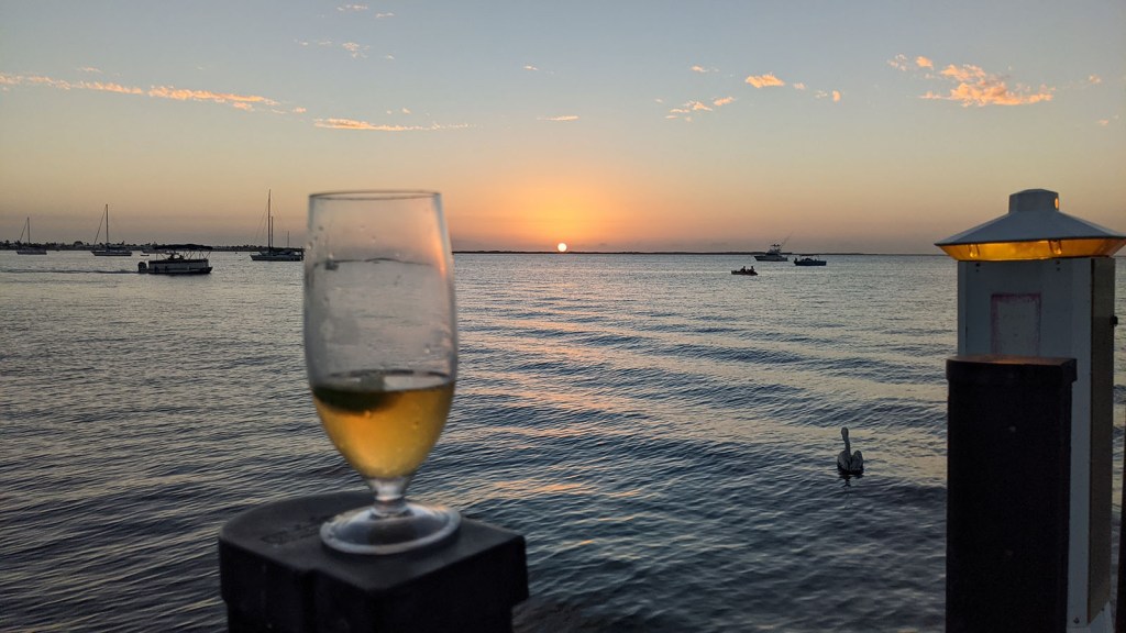 A beer in a glass on the dock at sunset