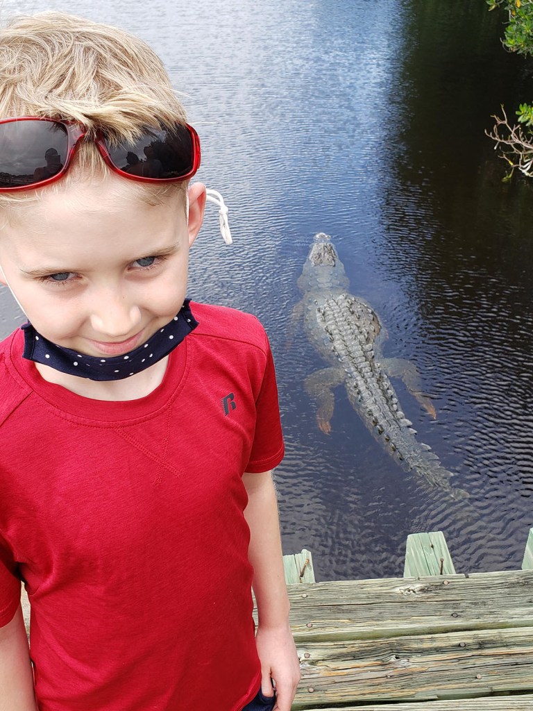 A boy in front of a large crocodile