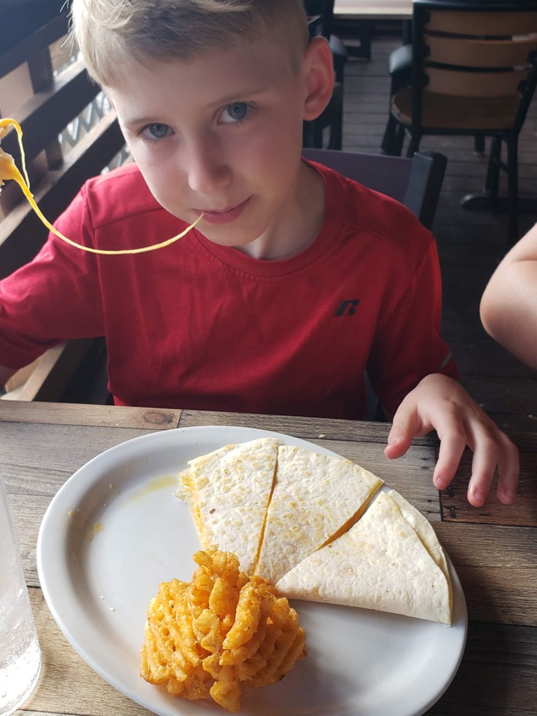 A boy eats a cheesy quesadilla