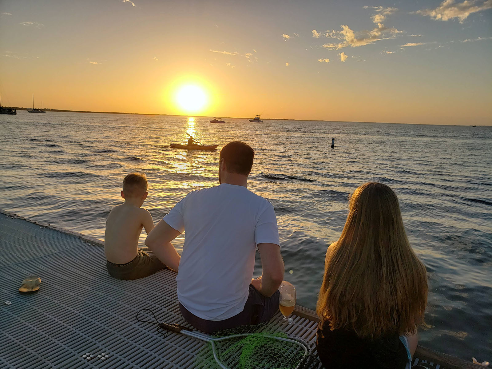 a family sitting on the dock at sunset