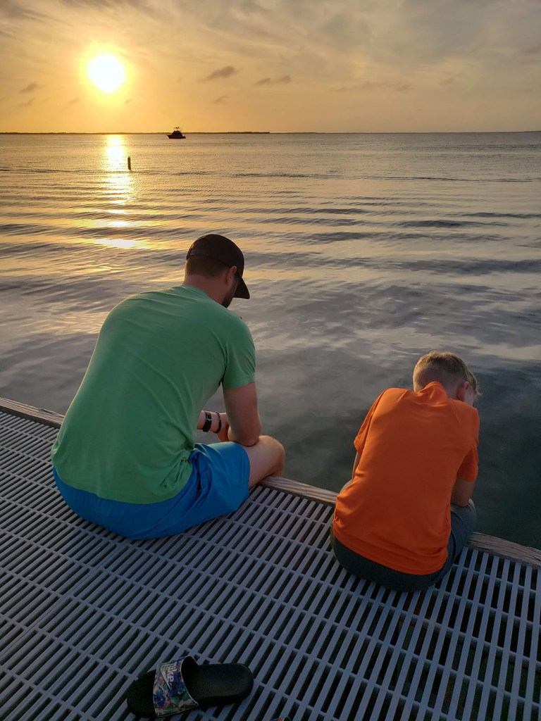 A boy and his father look off a dock