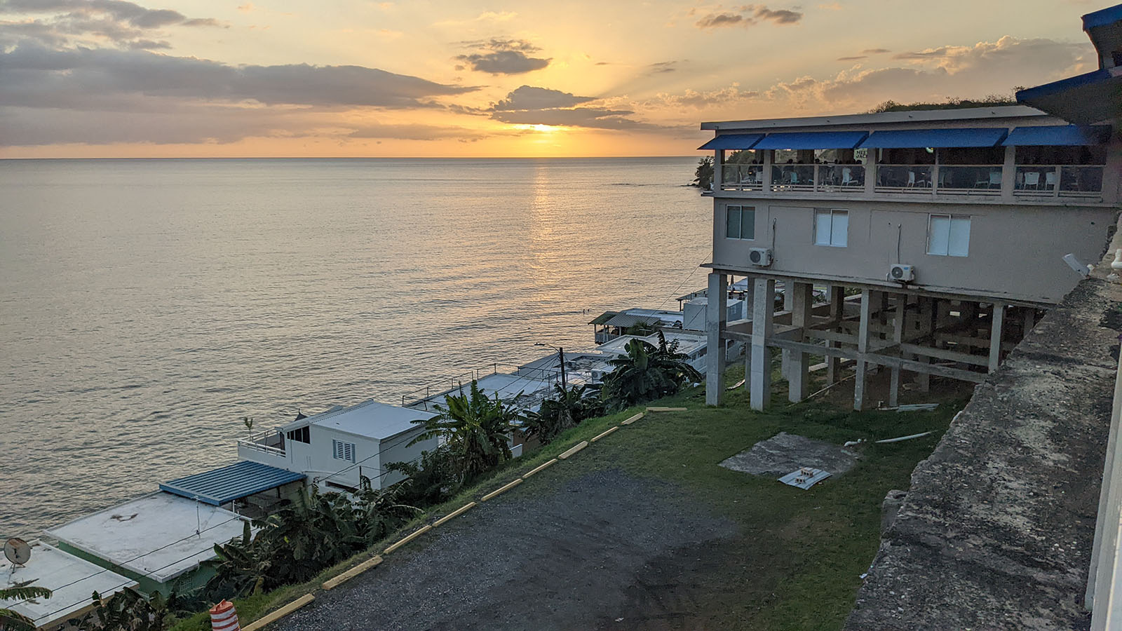 The sun setting over the ocean next to a restaurant