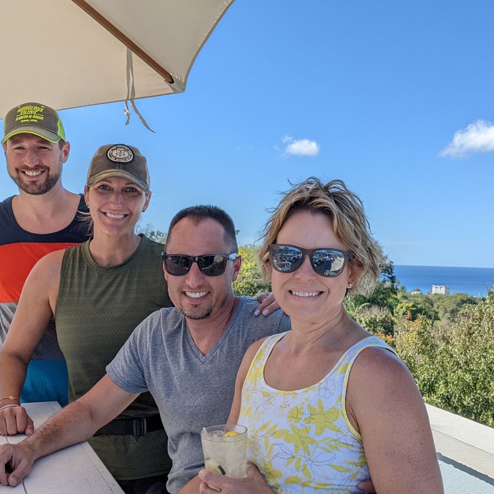 Two couples smiling at a table by the ocean