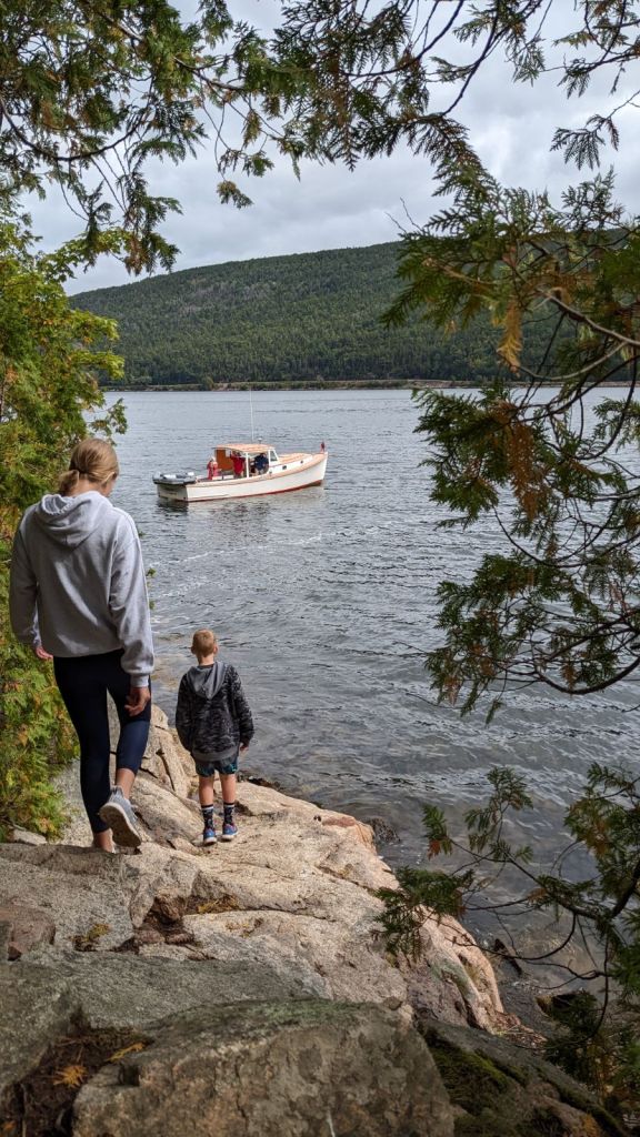 Two kids walking towards a boat taking pictures of falls by Acadia Mountain