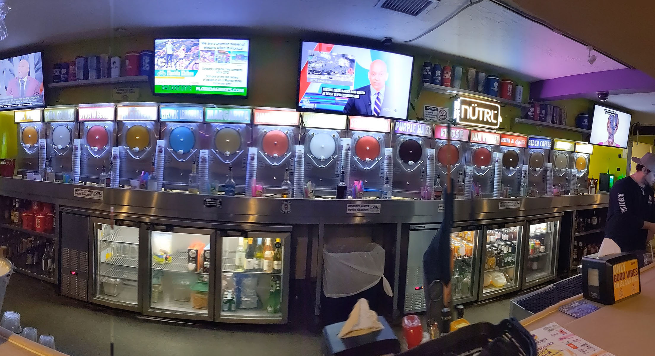 16 slushy daquiri machines are in a line with various colors of daquiri goodness