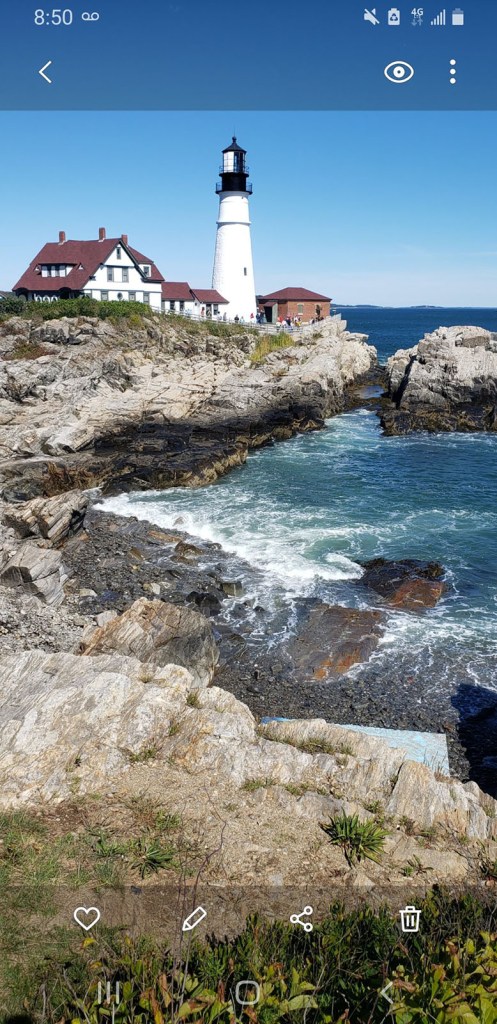 A white lighthouse sits on top of a rocky coast