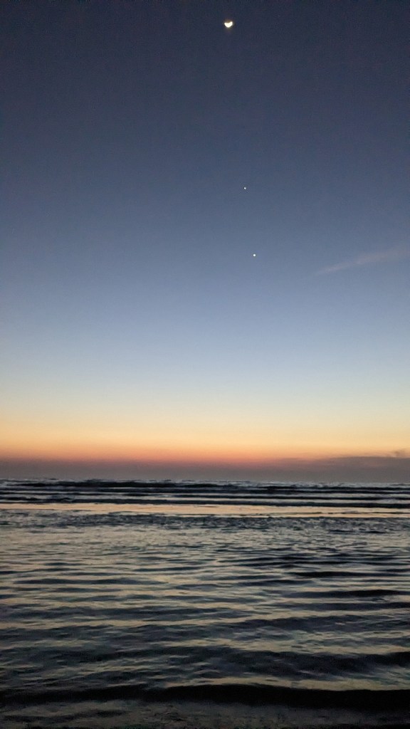 A crescent moon with what appears to be two stars directly below it. It is Venus and Jupiter.