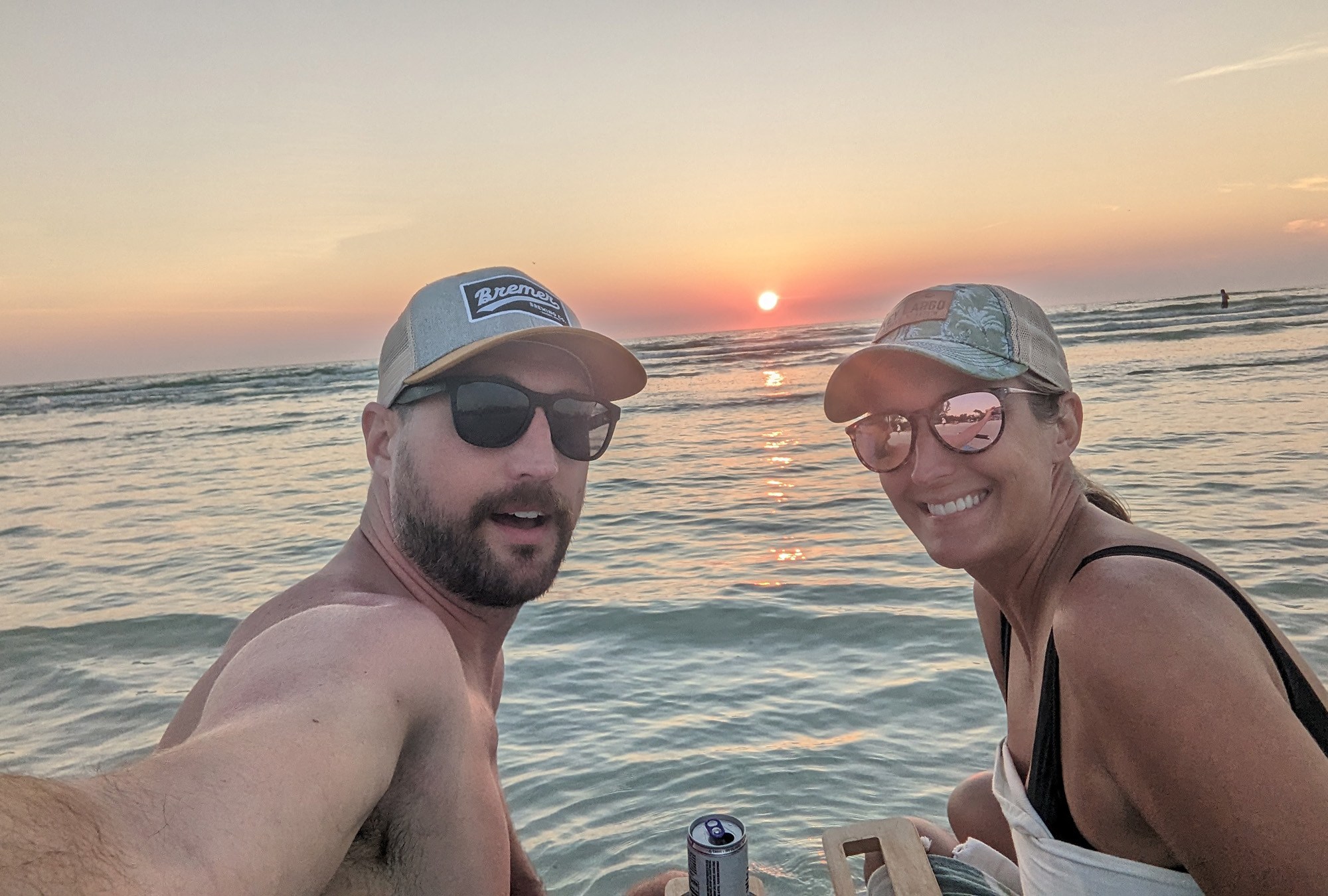 A couple in baseball caps smiles at the camera.