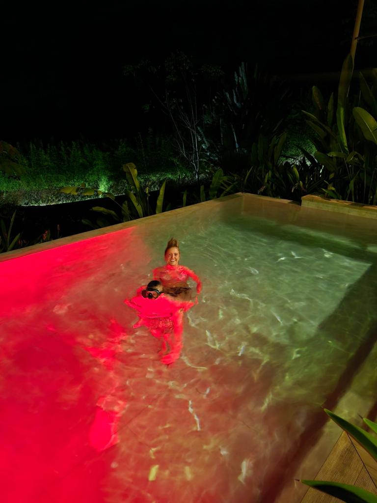 Kids swimming in our pool with red lights in the water