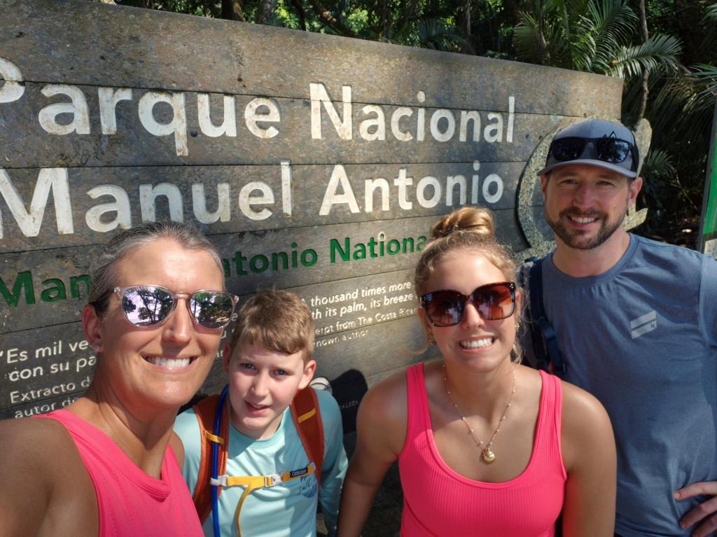 A family standing in front of a sign that reads Parque Nacional Manuel Antonio