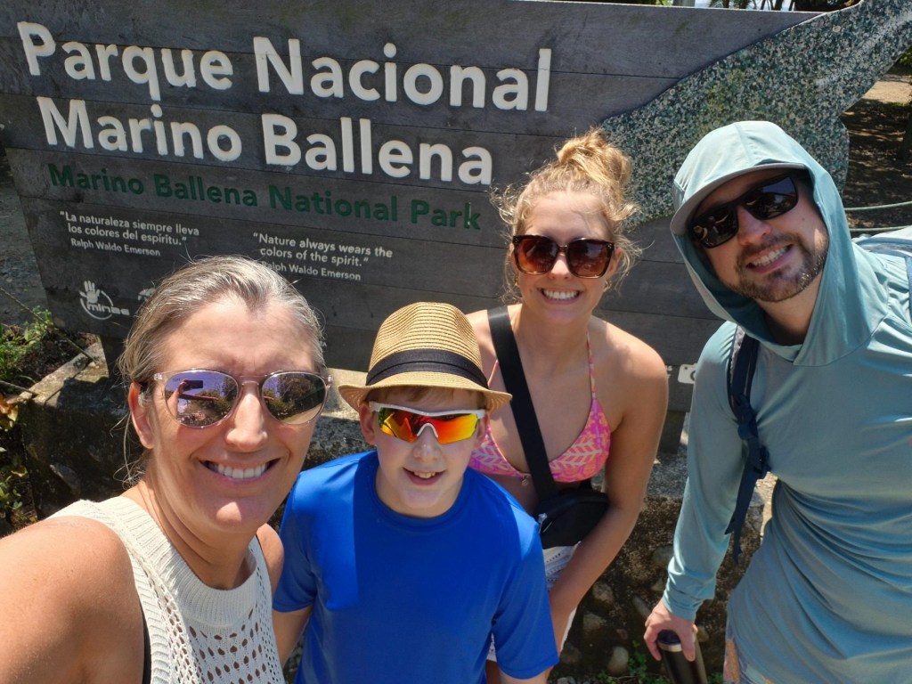 Marino Ballena National Park sign with a family of four smiling in front