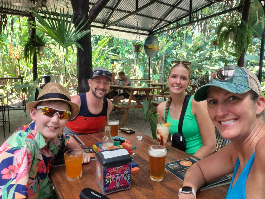 A family of four smiling at the camera at a table with drinks