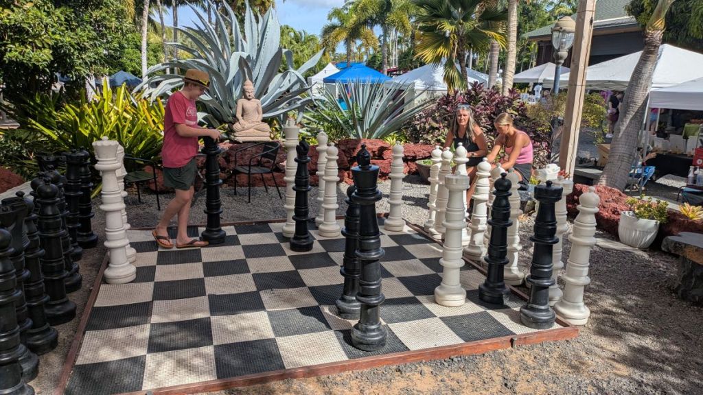 A boy plays chess on a huge chess board.
