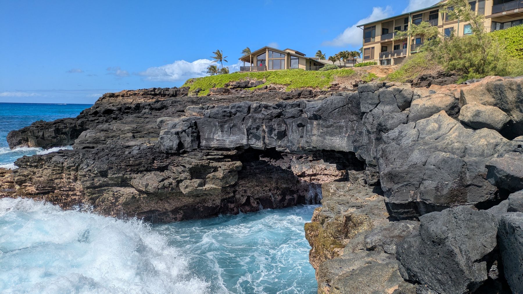 Beautiful house sits over the ocean churning beneath a bluff.