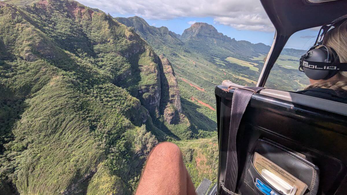A leg hangs out of the helicopter with green mountains under