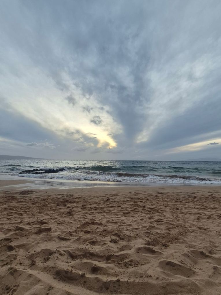 Clouds are over the waves of the Pacific washing up on the sandy beach
