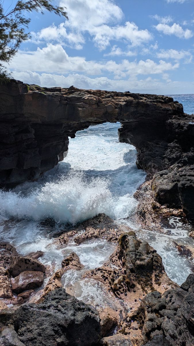 Waves crash under the Lava Arch near Maha'ulepu Heritage Trail