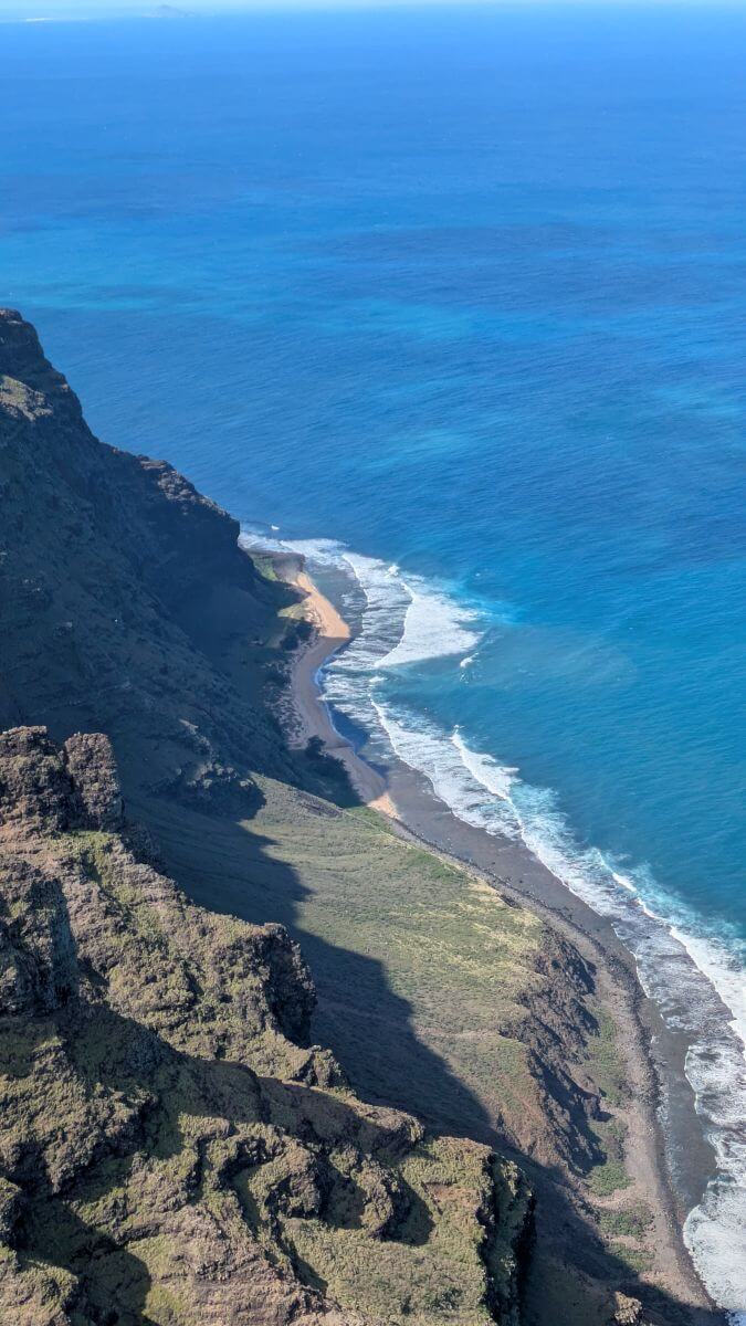 A secluded white beach is sandwiched between the enormous bluffs and the endless ocean