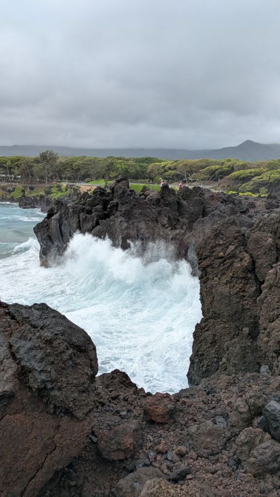 Waves crash against the black cliffs